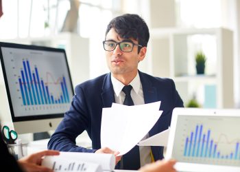 Consulting with colleague Young economist talking to colleague and explaining financial papers
